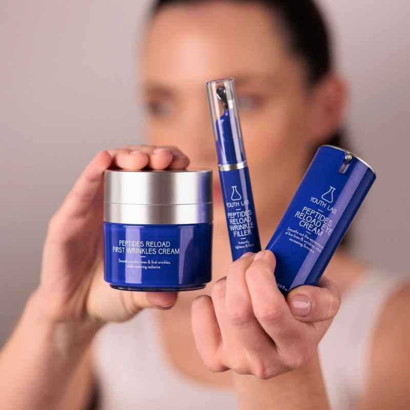 woman holding skincare products by youth lab, Peptides Reload series